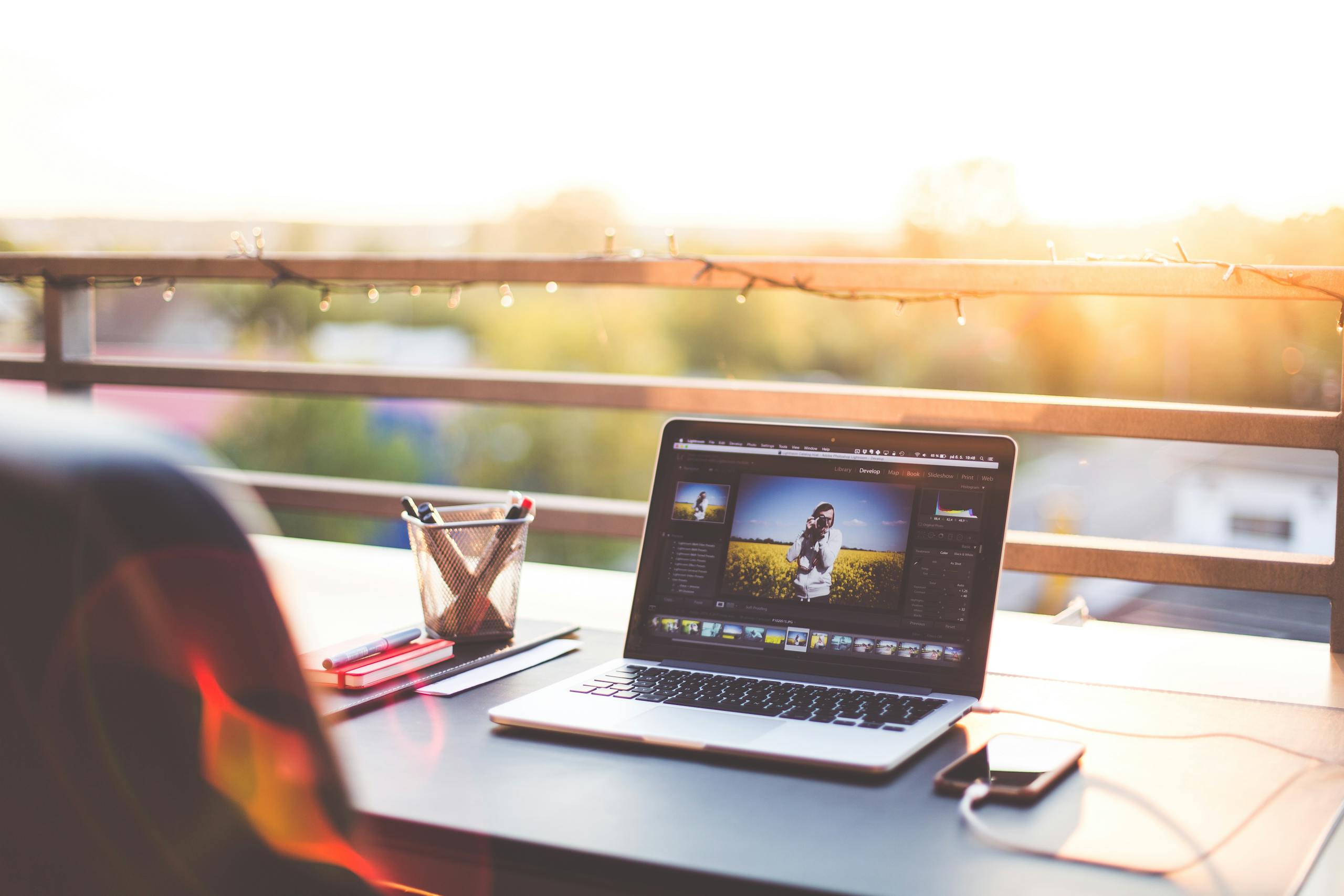 Laptop On An Outdoor Workstation A modern workspace on a balcony with a laptop and smartphone during sunset, capturing a creative work environment.